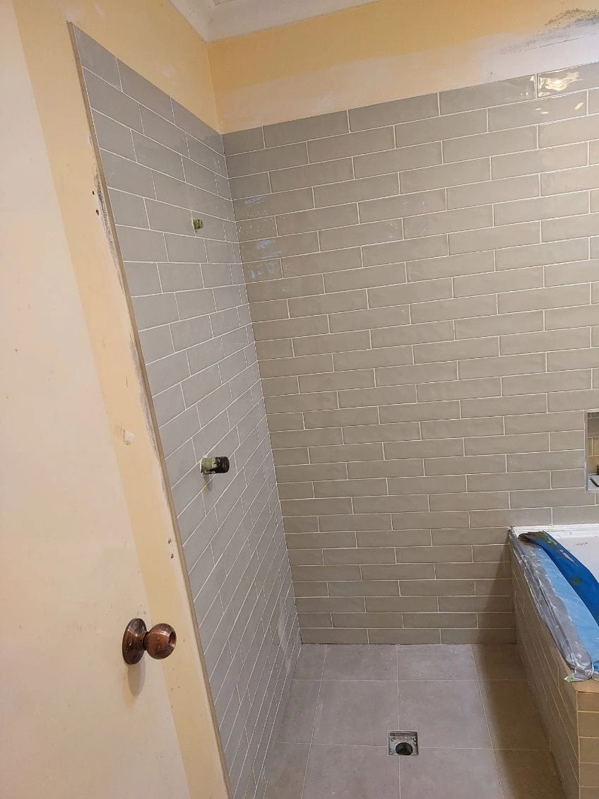 Soft grey rectangular tiles installed across a shower wall