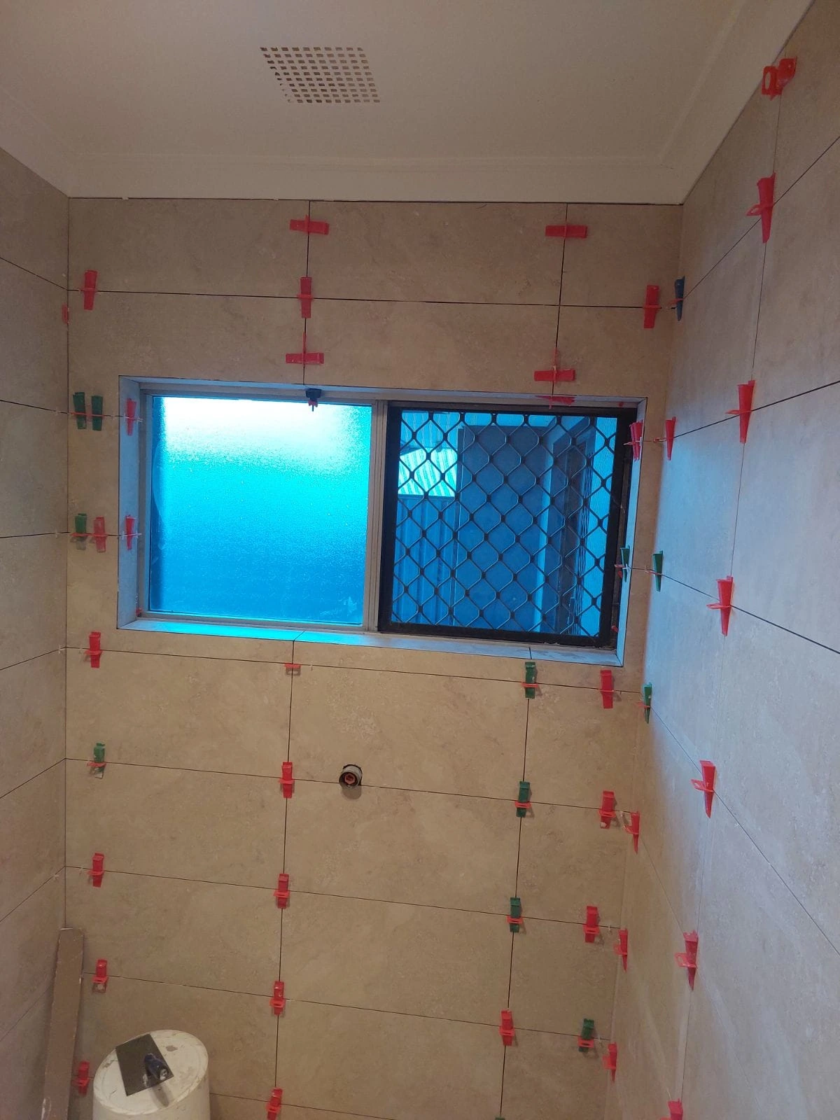 Neutral wall tiles being installed around a bathroom window