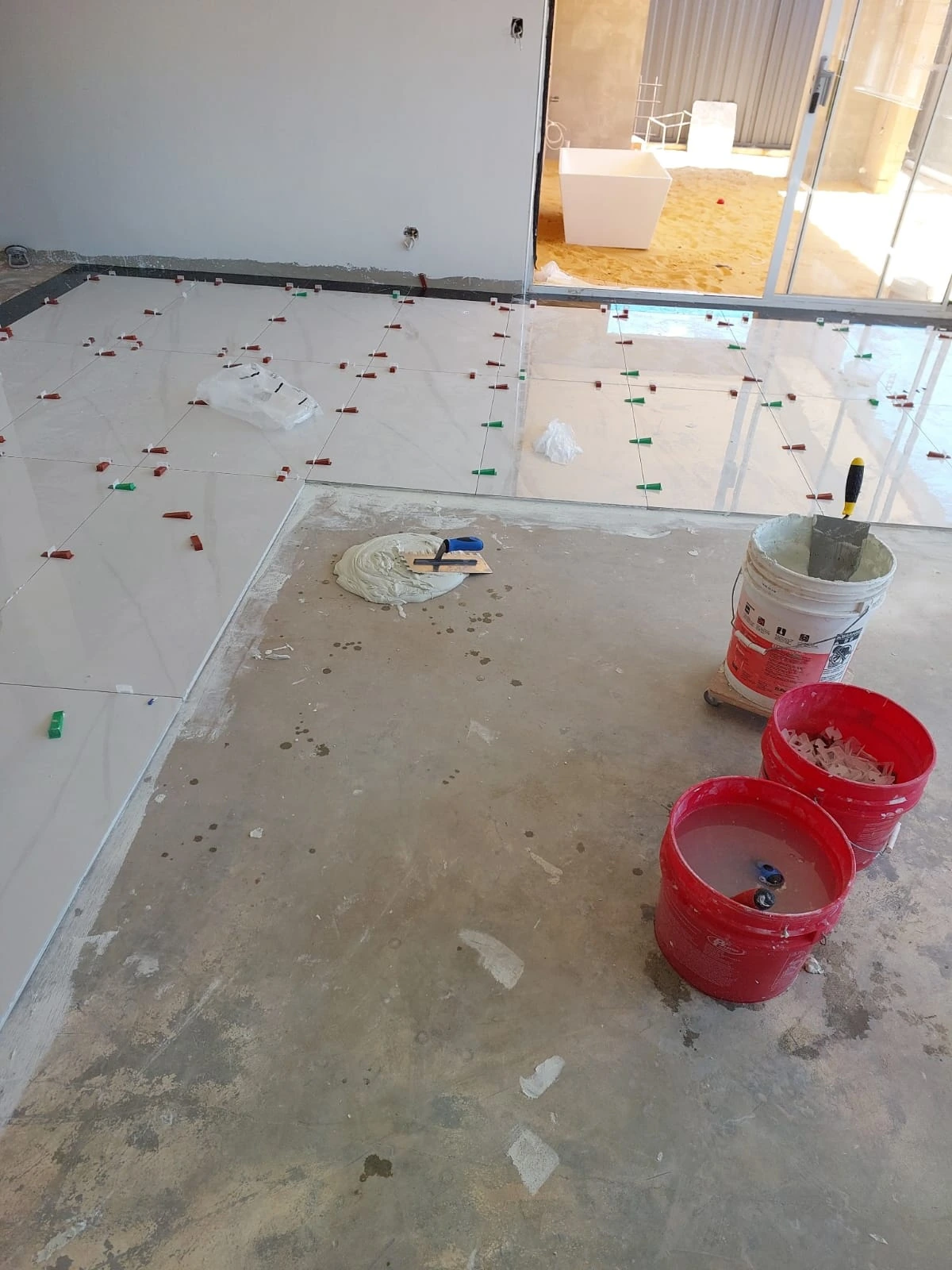Pale floor tiles being installed across an open-plan interior