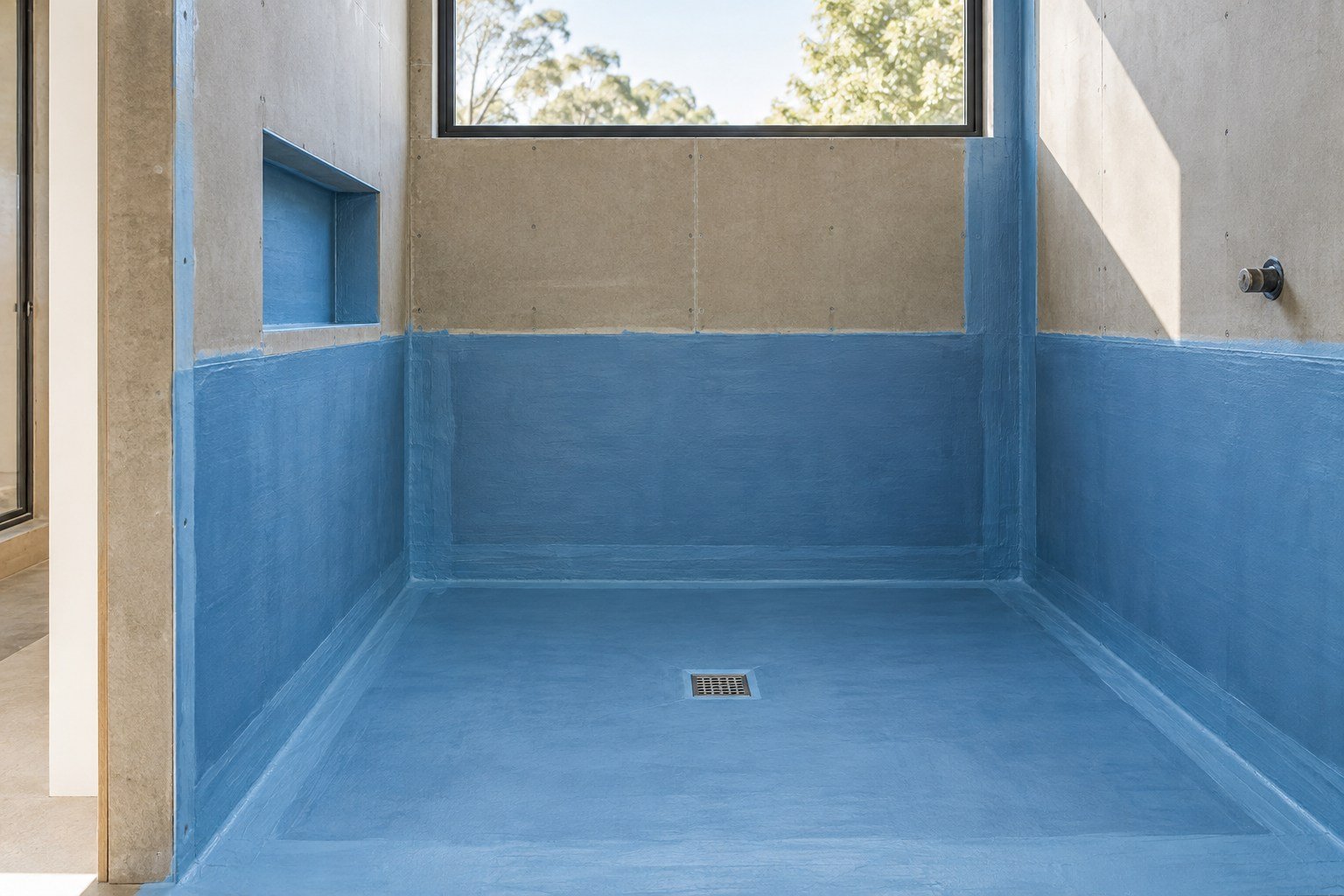 Evenly sealed blue waterproofing membrane in a prepared shower area